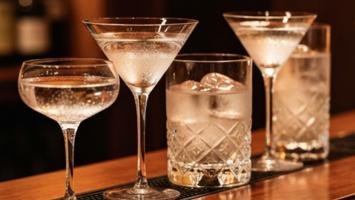 Eleganta cocktailglas på mörk bardisk i varm bakgrundsbelysning
