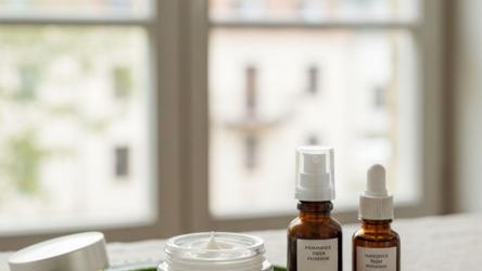 Ansiktskrämer i glasburk på linne med naturliga ingredienser i dagsljus